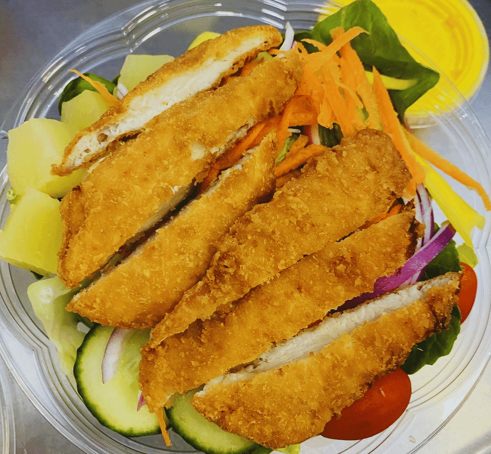 Breaded chicken salad with cucumbers, tomatoes, carrots, and pineapple in a clear bowl.