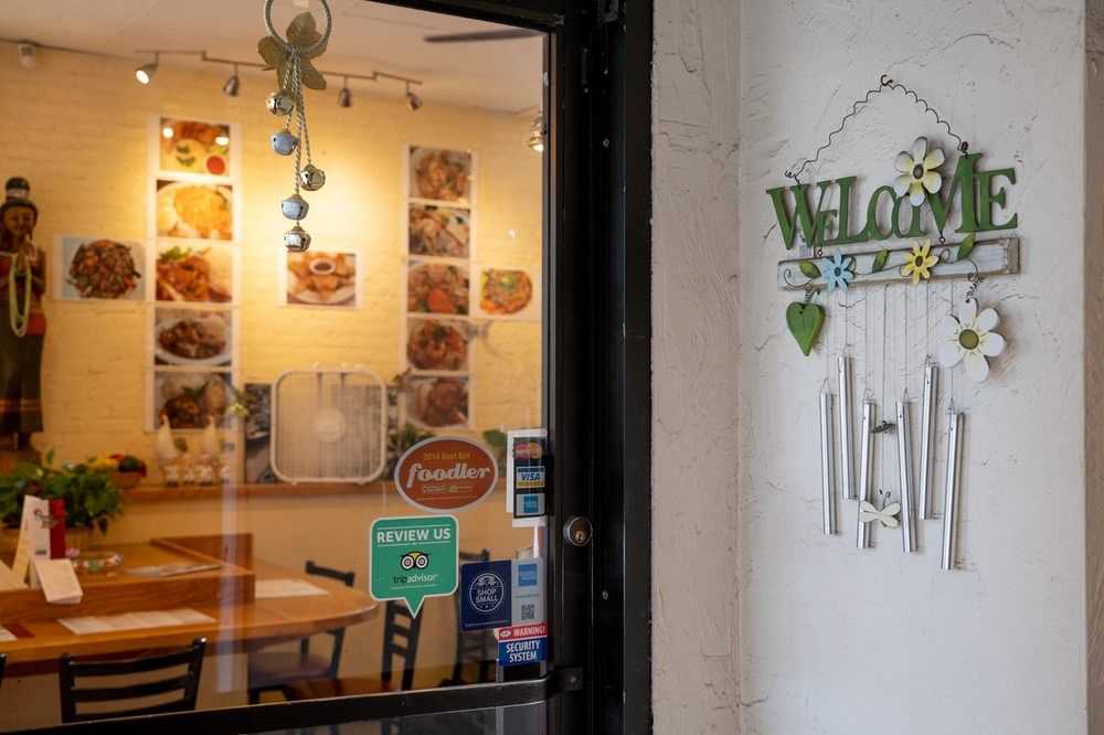 Welcome sign by the door of a cozy restaurant showing dishes inside.