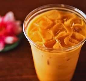 Chilled iced tea in a clear cup with floral decoration in the background.